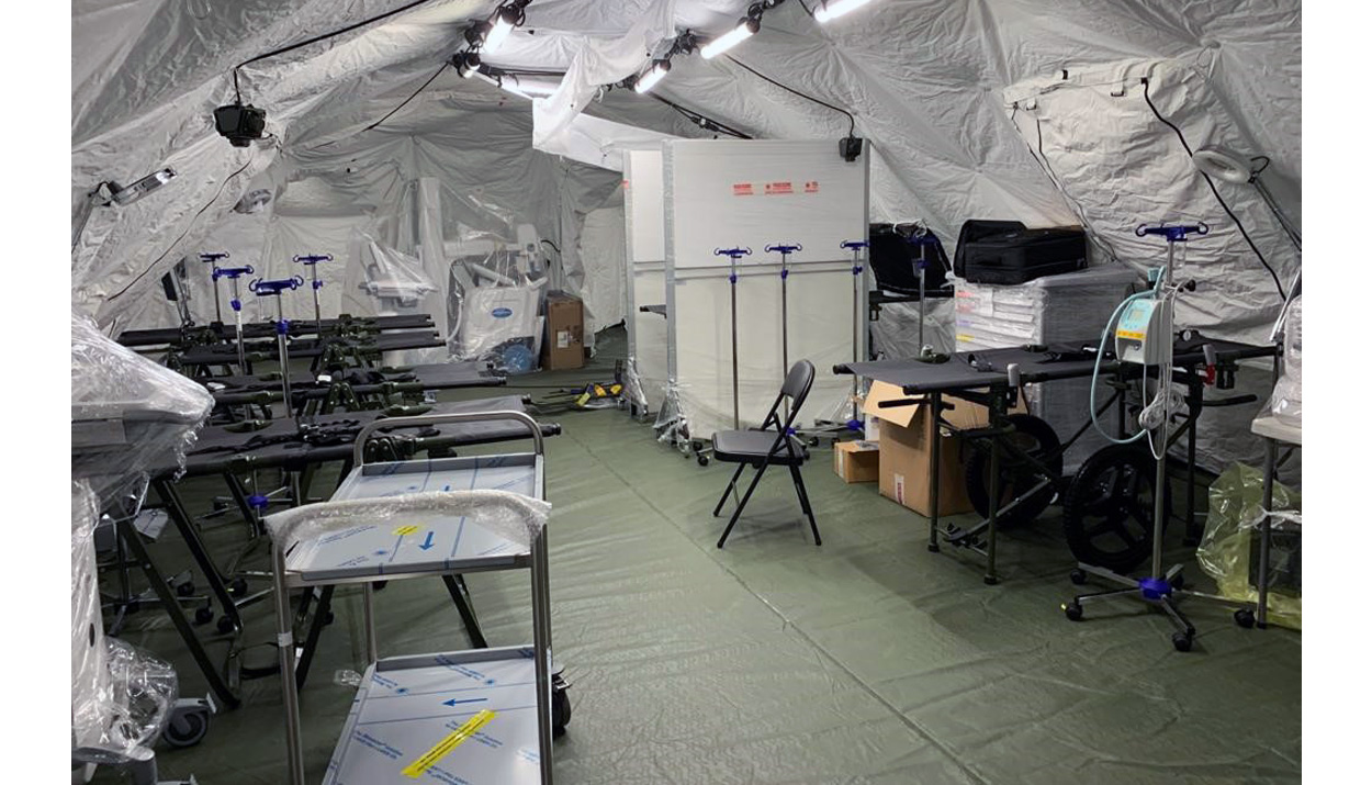 NATO field hospital interior: FH stainless steel intrument trolley in the foreground, a PRECISO medication trolley on the left and several IV poles