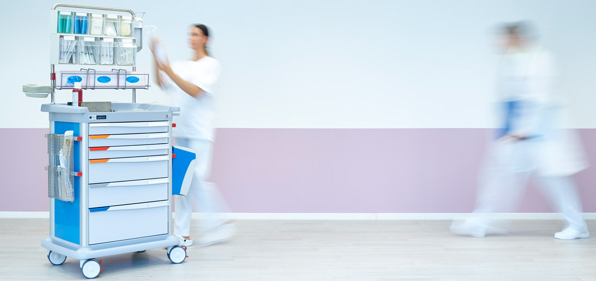 Nurse accesses the Preciso med trolley while other nurse walks by in background