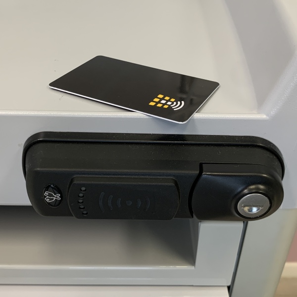 Electronic lock with RFID keycard reader and backup key on a Francehopital medication cart, with a black keycard resting on the top.